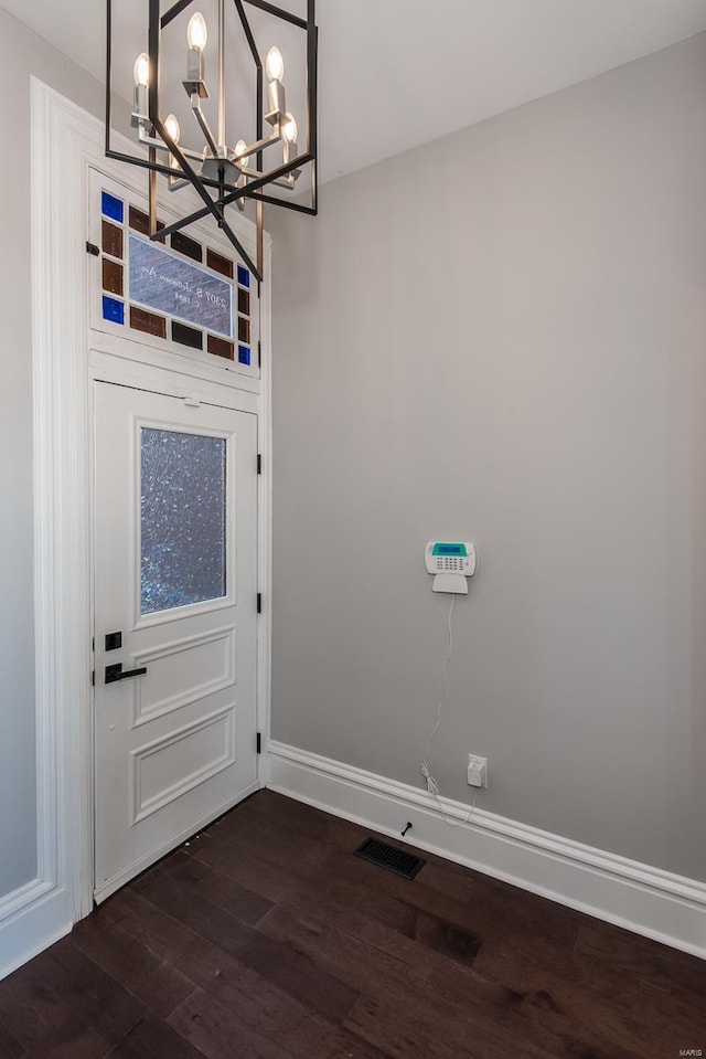 doorway to outside with dark wood-type flooring and a notable chandelier