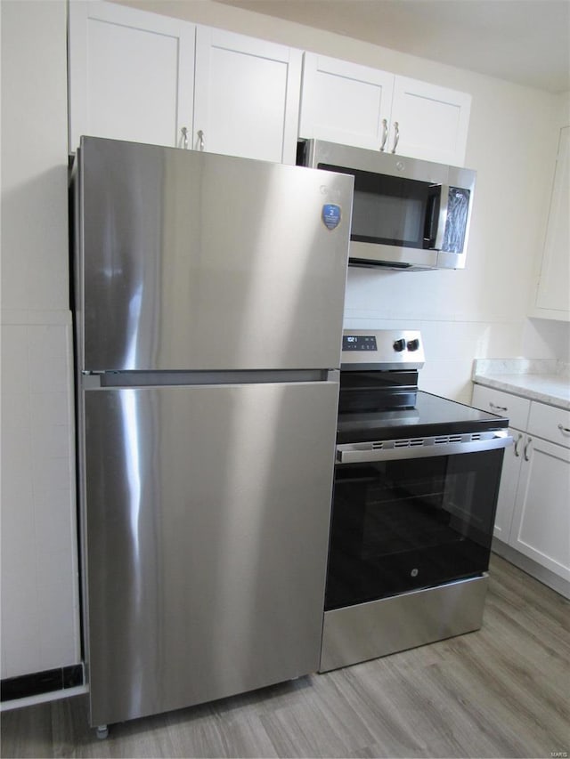 kitchen with white cabinets, appliances with stainless steel finishes, and light hardwood / wood-style floors