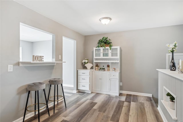 bar with white cabinetry and light hardwood / wood-style floors