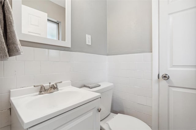 bathroom with vanity, toilet, and tile walls