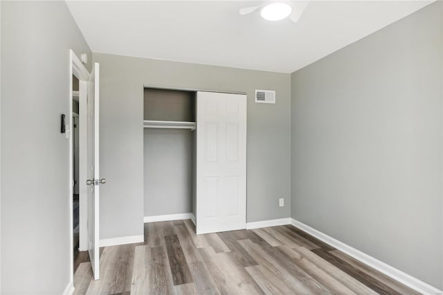 unfurnished bedroom with ceiling fan, light hardwood / wood-style flooring, and a closet