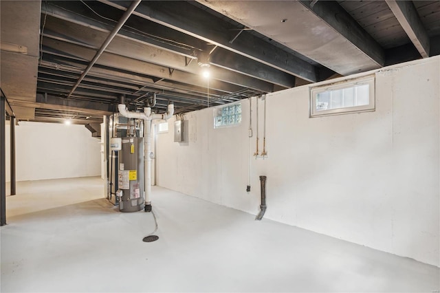 basement featuring a wealth of natural light, water heater, and electric panel