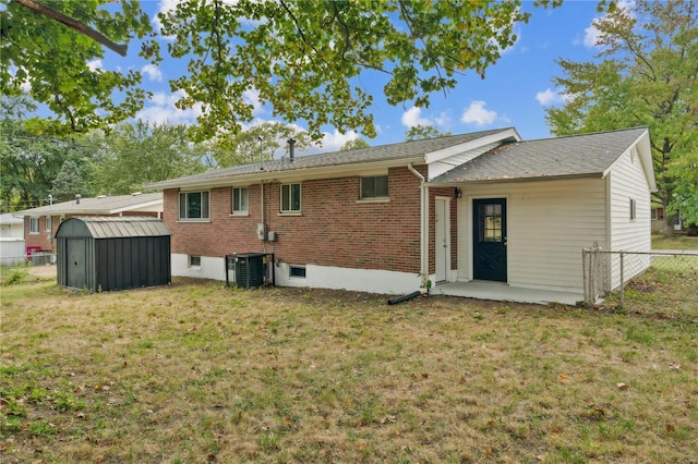 back of property with a storage unit, a yard, and central air condition unit