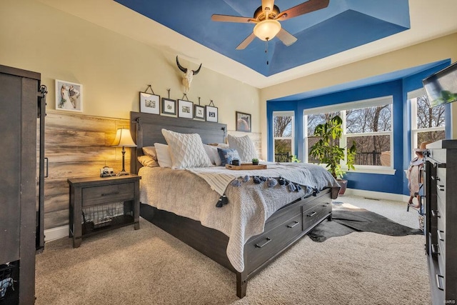 carpeted bedroom with ceiling fan and a tray ceiling