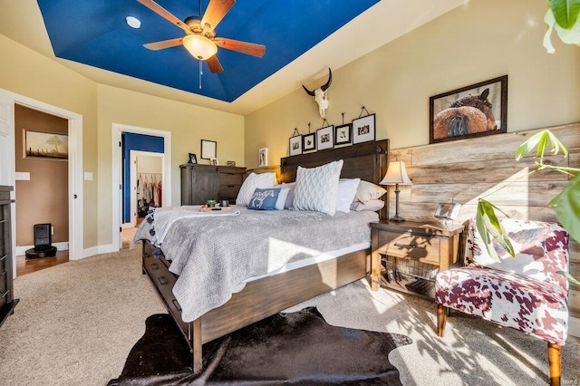 bedroom featuring ceiling fan, carpet, a tray ceiling, a walk in closet, and a closet