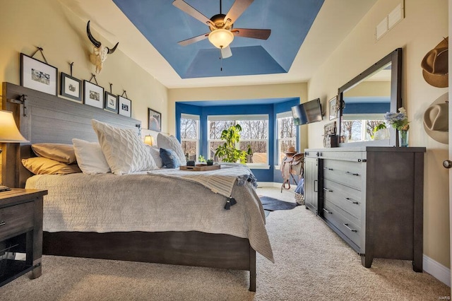 carpeted bedroom featuring ceiling fan and a raised ceiling