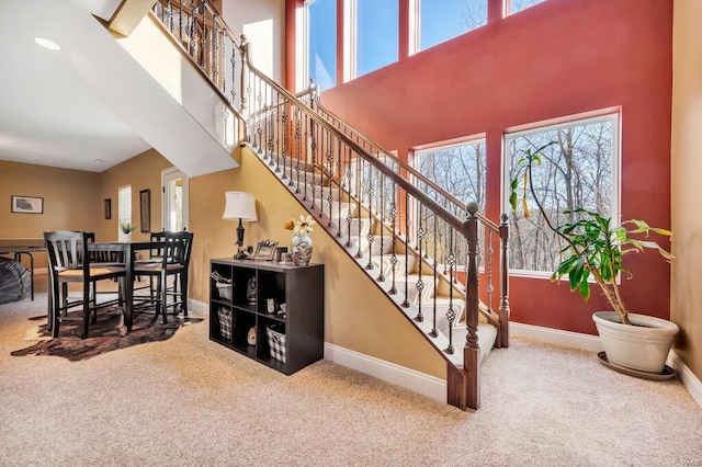 stairs featuring a towering ceiling and carpet floors