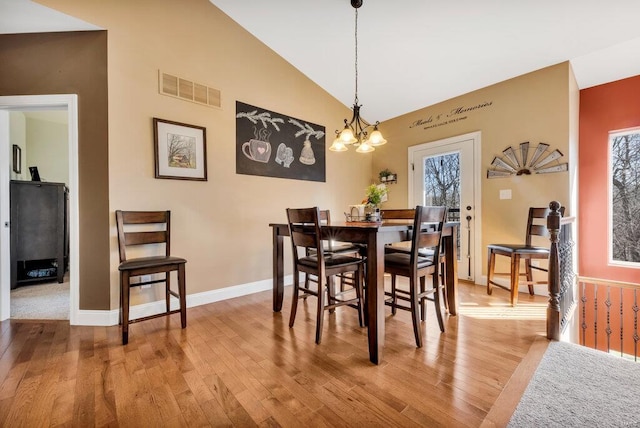 dining space featuring lofted ceiling, wood-type flooring, and a chandelier