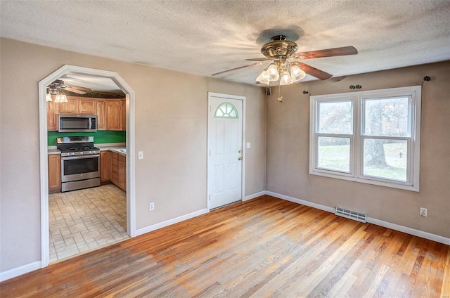 unfurnished room with ceiling fan, light hardwood / wood-style floors, and a textured ceiling