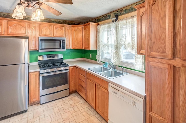 kitchen featuring a textured ceiling, stainless steel appliances, ceiling fan, and sink