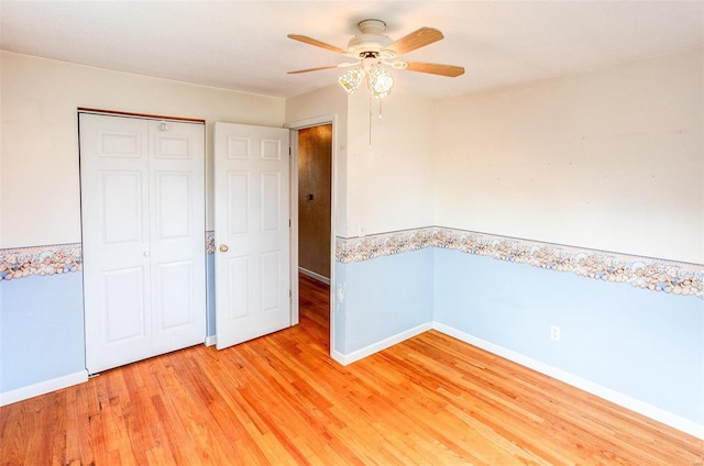 unfurnished bedroom with ceiling fan, a closet, and hardwood / wood-style flooring