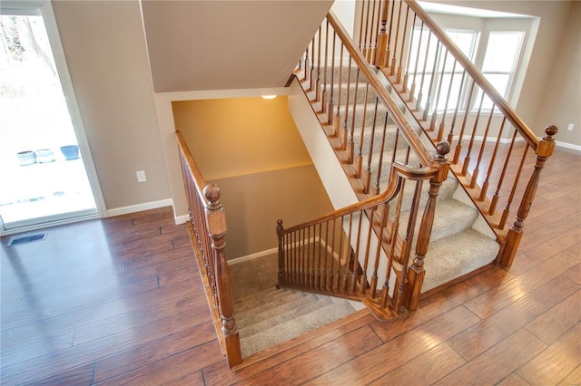 staircase with wood finished floors, visible vents, and baseboards