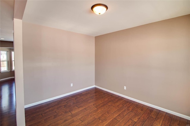 unfurnished room with dark wood finished floors and baseboards