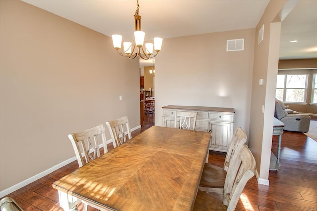 dining space featuring dark wood-style floors, baseboards, visible vents, and an inviting chandelier