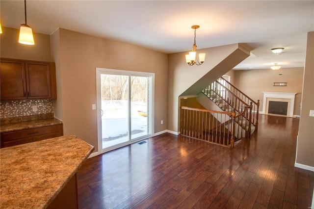 interior space with dark wood-style floors, brown cabinetry, decorative light fixtures, and a fireplace