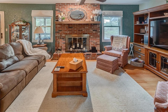 living room with a fireplace, light hardwood / wood-style floors, a wealth of natural light, and ceiling fan