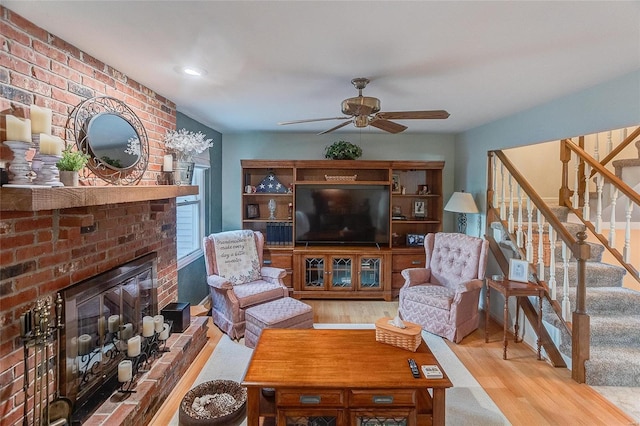 living room featuring wood-type flooring, a brick fireplace, and ceiling fan