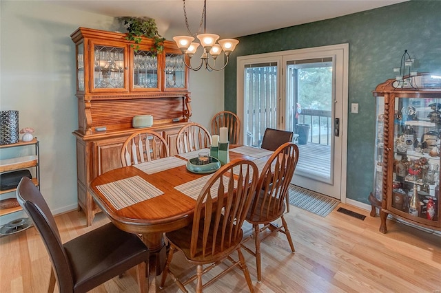 dining area with light wood-type flooring and a notable chandelier