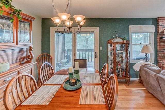 dining room with a wealth of natural light, light hardwood / wood-style floors, and an inviting chandelier