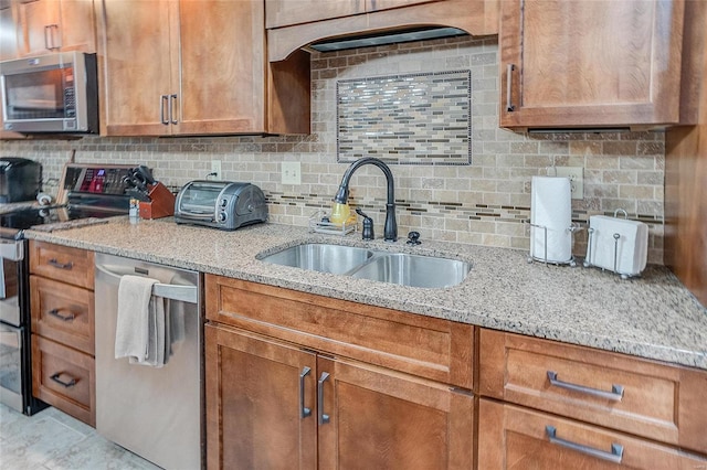 kitchen with light stone countertops, backsplash, stainless steel appliances, and sink