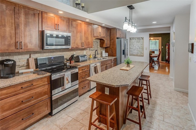 kitchen with a kitchen bar, appliances with stainless steel finishes, tasteful backsplash, pendant lighting, and a center island