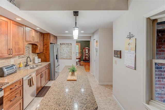 kitchen featuring sink, light stone counters, backsplash, pendant lighting, and appliances with stainless steel finishes