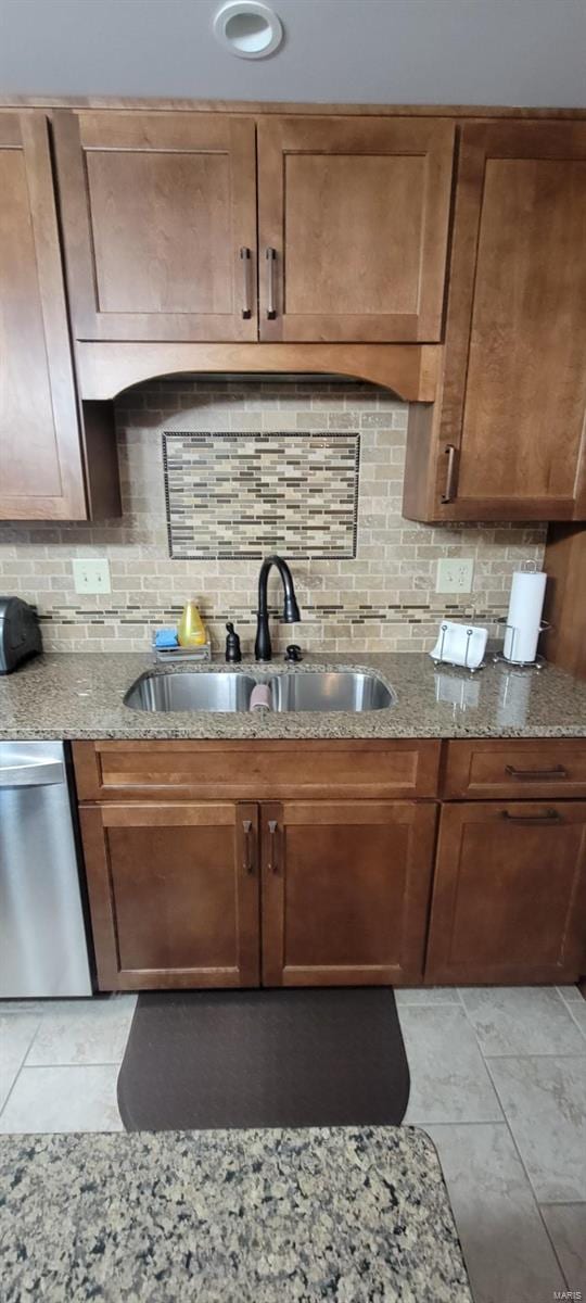 kitchen with dishwasher, decorative backsplash, light stone countertops, and sink