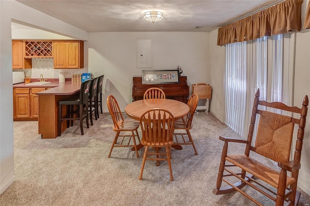 dining space with light carpet, electric panel, and sink