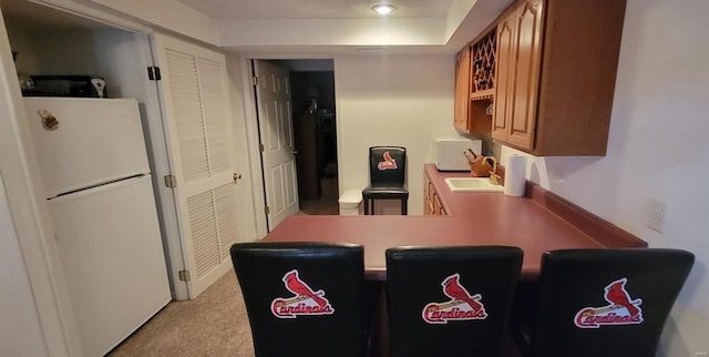 kitchen featuring sink, white appliances, and light carpet