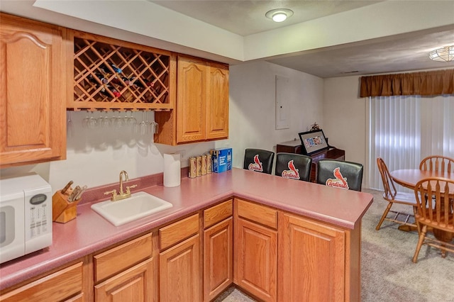 kitchen with kitchen peninsula, light colored carpet, and sink