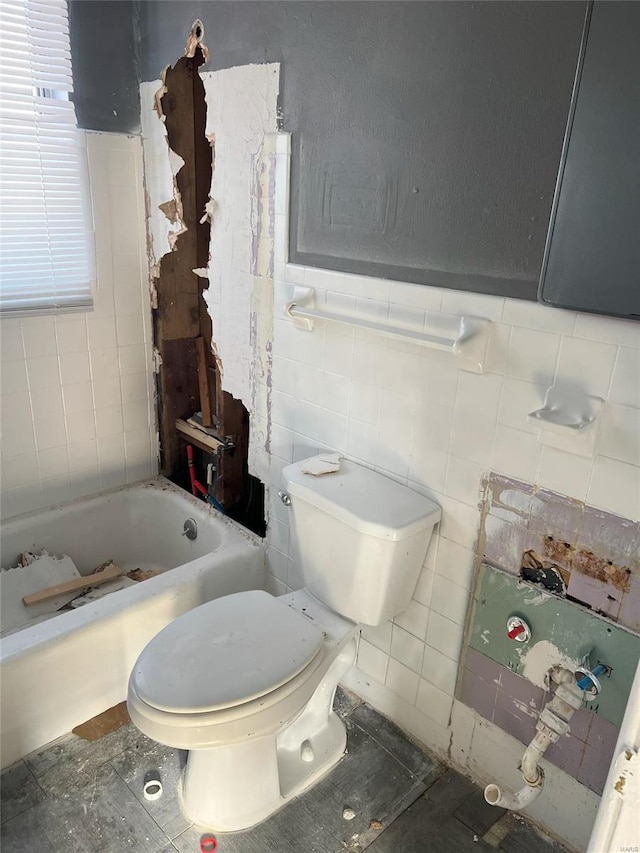 bathroom with toilet, tile walls, and a washtub