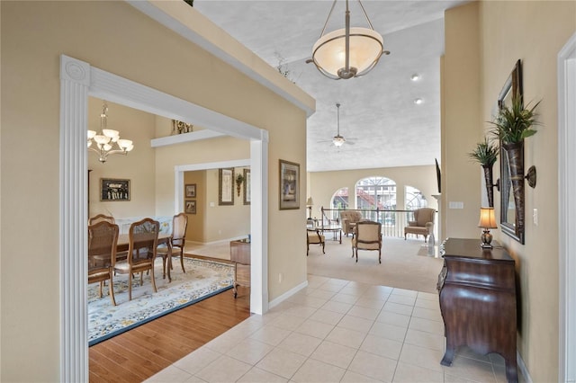 foyer entrance featuring ceiling fan with notable chandelier, light tile patterned floors, and lofted ceiling