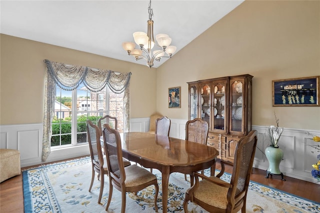 dining area featuring hardwood / wood-style floors, lofted ceiling, and an inviting chandelier