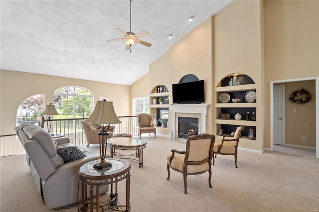 carpeted living room with ceiling fan, built in features, and high vaulted ceiling