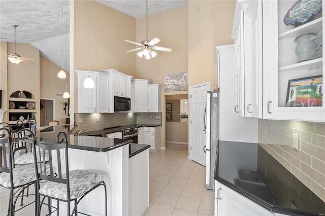 kitchen with kitchen peninsula, appliances with stainless steel finishes, a kitchen bar, high vaulted ceiling, and white cabinetry