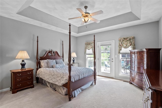 carpeted bedroom with a tray ceiling, ceiling fan, and access to outside