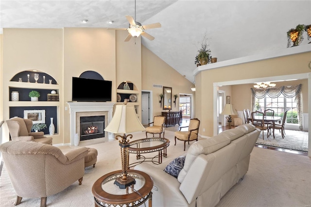 carpeted living room with vaulted ceiling, built in shelves, and ceiling fan with notable chandelier