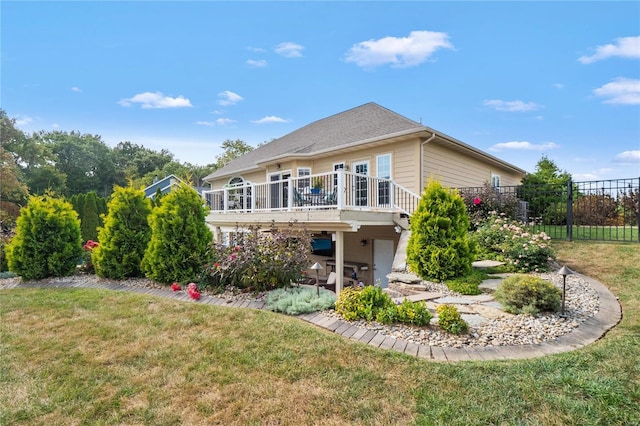 rear view of house featuring a lawn and a deck