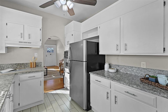 kitchen featuring ceiling fan, white cabinets, light stone counters, and stainless steel refrigerator