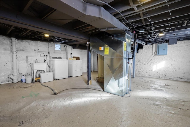 basement with heating unit, sink, independent washer and dryer, and electric panel