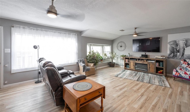 living room with a textured ceiling, light wood-type flooring, ceiling fan, and lofted ceiling