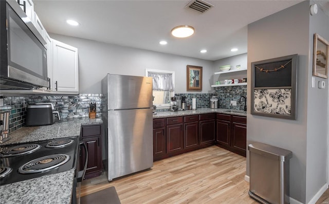 kitchen featuring sink, light hardwood / wood-style flooring, appliances with stainless steel finishes, tasteful backsplash, and light stone counters