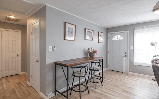 entrance foyer featuring crown molding, light hardwood / wood-style floors, and a textured ceiling