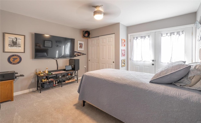 bedroom featuring two closets, french doors, light colored carpet, and ceiling fan