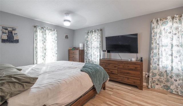 bedroom with light wood-type flooring, multiple windows, and ceiling fan