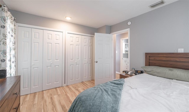 bedroom with light hardwood / wood-style floors and multiple closets