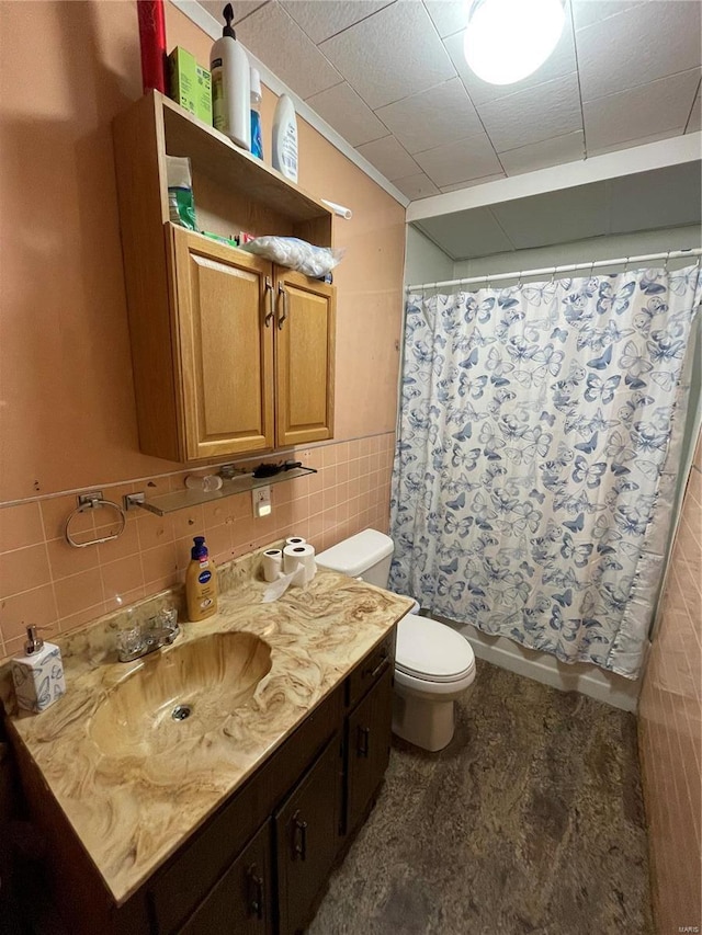 bathroom with vanity, toilet, and tile walls