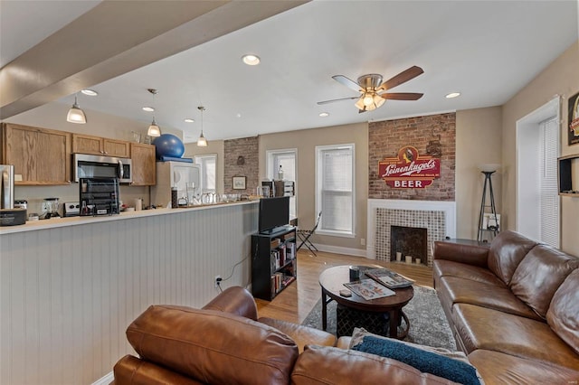 living room featuring a fireplace, a wealth of natural light, light hardwood / wood-style floors, and ceiling fan