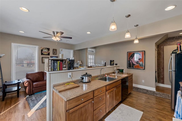 kitchen with black dishwasher, hanging light fixtures, dark wood-type flooring, and sink