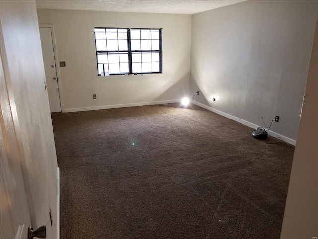 empty room with a textured ceiling and dark colored carpet